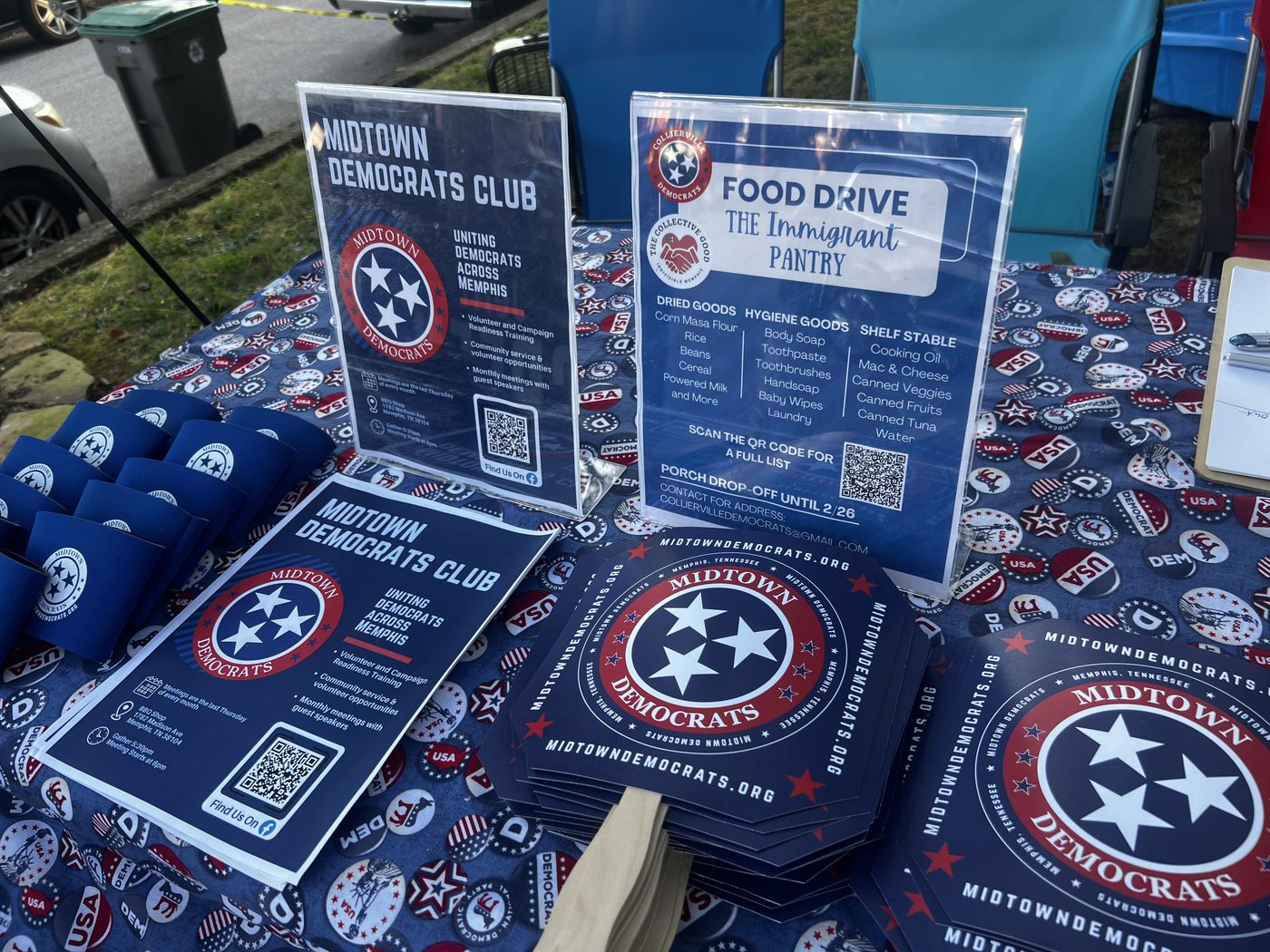 The club's festival table: Midtown Democrats flyers, tri-star stickers and hand fans printed with midtowndemocrats.org, beside a food-drive information sign.