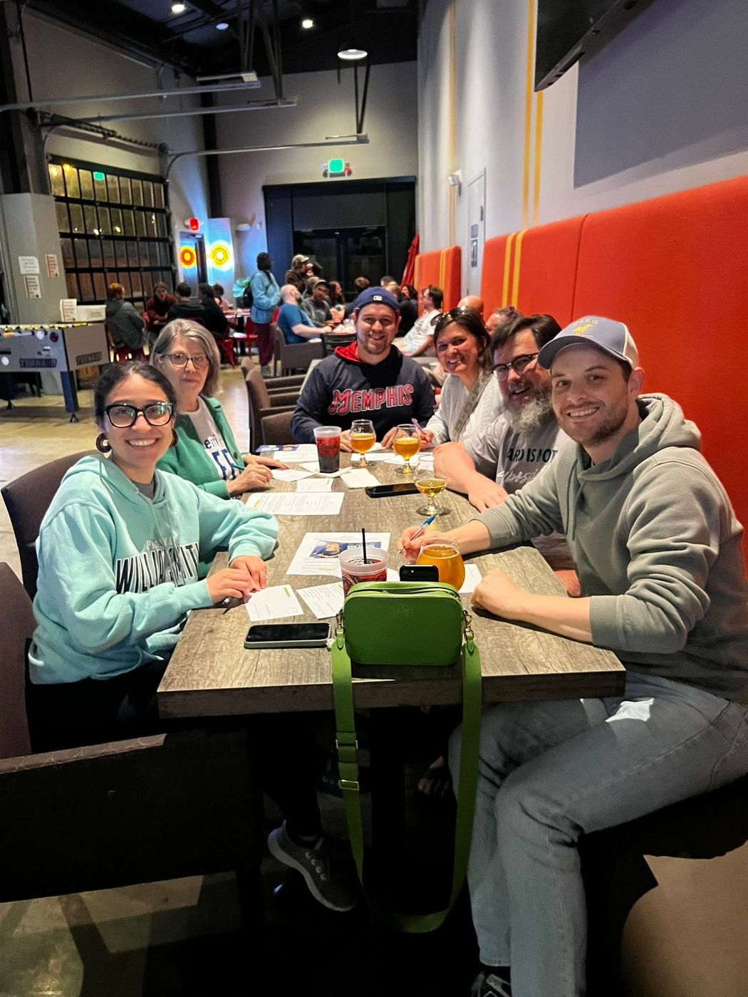 Club members gathered around a table writing postcards to voters at a local brewery.