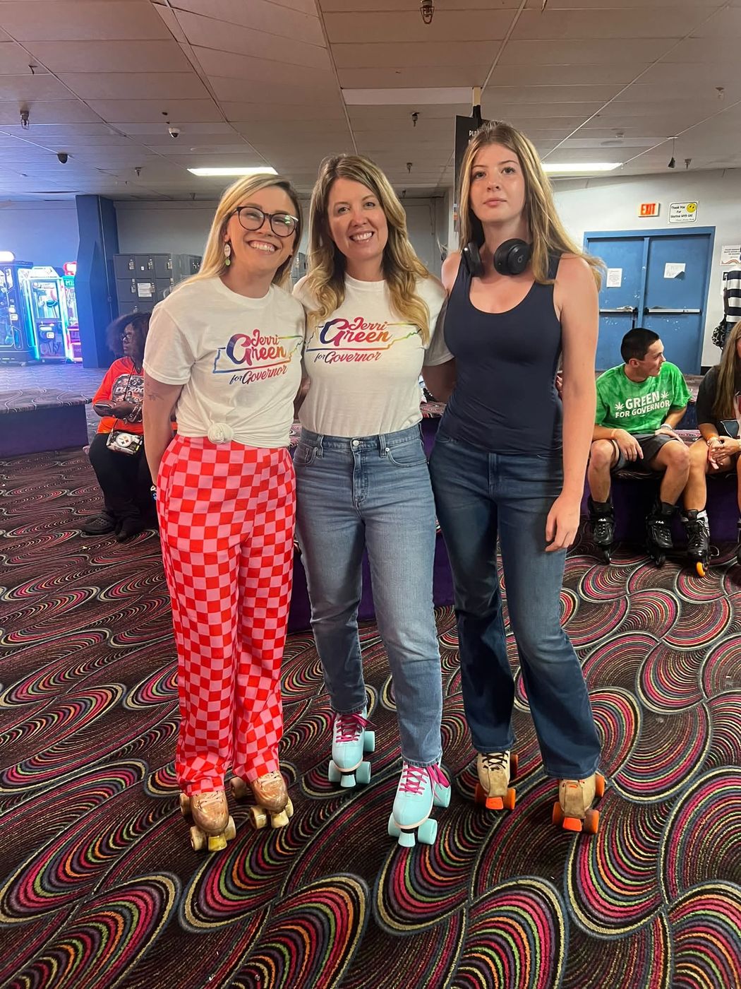 Three members in campaign T-shirts on roller skates at a club social at the skating rink.